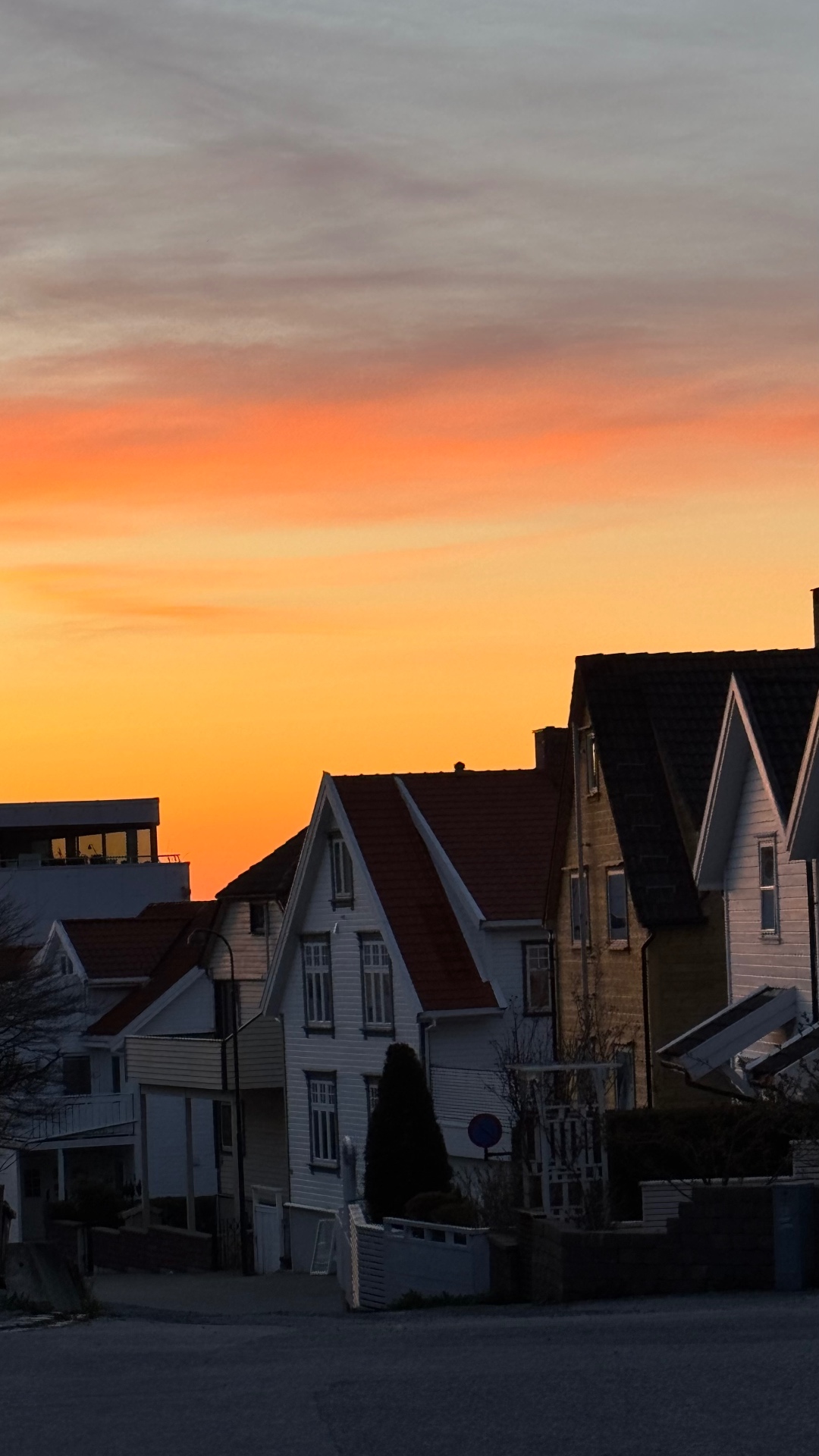 Hvite trehus på Storhaug i solnedgang med oransje himmel